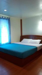 ein Schlafzimmer mit einem Bett mit einer blauen Decke und einem Fenster in der Unterkunft Jit Dee Home Khao Kho in Khao Kho