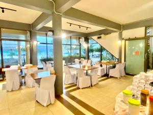 Ban Phang PhraoAlongkot Beach Resort Khanom的有白色桌椅和窗户的餐厅