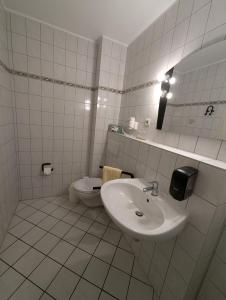 a white bathroom with a sink and a toilet at Landhotel Reith Fulda - Künzell in Fulda