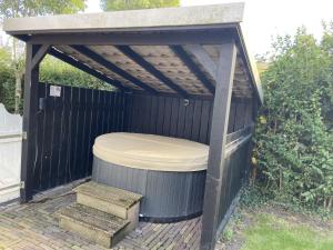 einen Pavillon mit einem Whirlpool und einer Bank in der Unterkunft Holiday Home Wiringherlant-10 by Interhome in Noordstroe