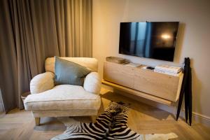 a living room with a tv and a chair and a zebra at Collection Luxury Accommodation Oudehoek Apartments in Stellenbosch