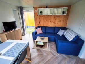 a living room with a blue couch and a tv at Holiday Home Tiny Haus Christas Angler-Oase by Interhome in Riedenburg