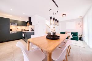 a kitchen and dining room with a wooden table and white chairs at Xzllenz - 4 Schlafzimmer, Zentral, Parken, U-Bahn, 2 Bäder, 4 Smart-TV, optional Einzelbett in Nürnberg +18 photos
