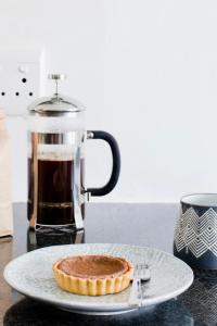 ケープタウンにあるAvenue One Apartmentsのコーヒーカップの横の皿の上のパイ