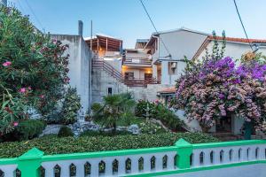 a house with a green fence and flowers at Apartments Draga in Sukošan