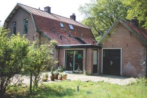 an old brick house with a large garage at Knusse retreat midden op de Veluwe in Hoenderloo
