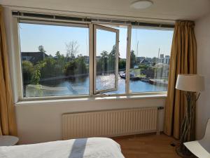 a bedroom with a window with a view of a river at Lemmer House - Luxe familiehuis aan het water in Lemmer