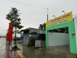 a building in the rain with a sign on it at Nhà Nghĩ Huỳnh Yên in Trà Vinh