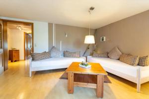 a living room with two white beds and a table at Haus Winterberg in Schonach