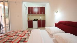 a room with a bed and a kitchen with red cabinets at Apartments Percobic in Sutomore