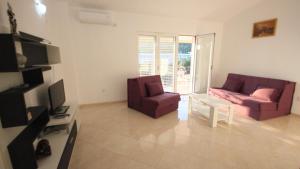 a living room with two chairs and a couch and a tv at Apartments Percobic in Sutomore