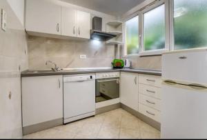 Apartment with sea view في أوباتيا: مطبخ بخزائن بيضاء ومغسلة ونافذة