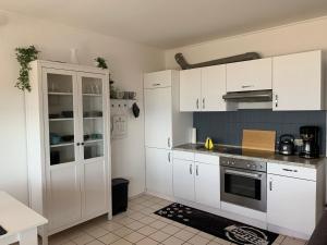 a kitchen with white cabinets and a stove top oven at Traumferienwohnung222 in Neustadt in Holstein