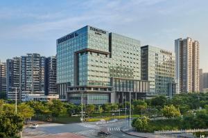 深圳深圳机场希尔顿逸林公寓的一座大玻璃建筑,位于城市前方