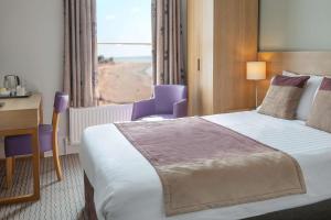 a hotel room with a bed and a desk and a window at Exmouth Beach Hotel in Exmouth