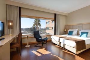 a hotel room with two beds and a desk and a window at TRYP by Wyndham Porto Expo Hotel in Leça da Palmeira