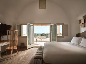 una camera da letto con un letto, una scrivania e una finestra di Sea Breeze Santorini Beach Resort, Curio By Hilton a Perivolos