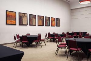 a room with tables and chairs and paintings on the wall at Country Inn & Suites by Radisson, BWI Airport Baltimore , MD in Linthicum Heights