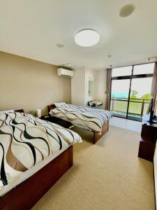two beds in a room with a large window at ジェムスティーイン川奈 in Ito