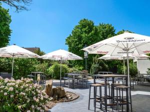 a patio with tables and chairs and umbrellas at Hotel Viva Bröckel in Bröckel