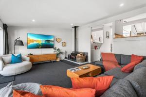 a living room with a gray couch and orange pillows at Urban Oasis - Central with Lakeview in Queenstown
