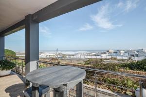 a table on a balcony with a view of the ocean at Wave song in Yzerfontein
