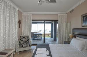 a bedroom with a bed and a chair and a balcony at Wave song in Yzerfontein +33 photos