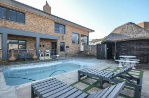 a swimming pool with two benches and a house at Wave song in Yzerfontein
