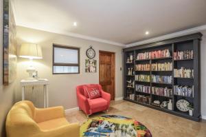 a living room with a red chair and book shelves at Wave song in Yzerfontein