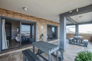 a patio with a bench and a room with windows at Wave song in Yzerfontein