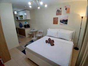 a bedroom with a white bed with a pair of shoes on it at Mountain View Studio at Marina Spatial - 300Mbps, Pool, City Centre in Dumaguete