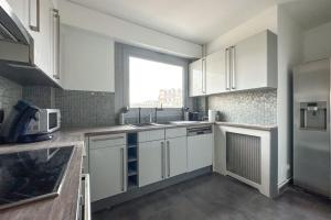 Una cocina con gabinetes blancos y una ventana grande. en Flexliving - room - Ternes, en París