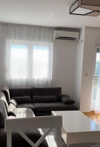 a living room with a black couch and two windows at Apartment Shine in Konik