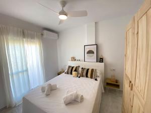 een witte slaapkamer met een bed met witte lakens en kussens bij Dúplex Romero y Alba in Sanlúcar de Barrameda