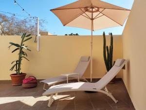een paar stoelen en een parasol op een patio bij Dúplex Romero y Alba in Sanlúcar de Barrameda
