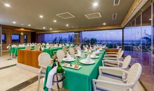 uma sala de jantar com mesas verdes e cadeiras brancas em Sherwood Dreams Resort em Belek