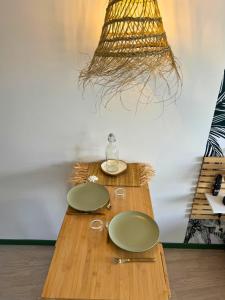 une table en bois avec deux assiettes vertes et une lampe dans l'établissement Oasis - Wifi, Clim, Vue, Équipé, à Lourdes 9 autres photos
