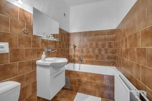 a bathroom with a sink and a tub and a toilet at Hotel PODKOST in Libošovice