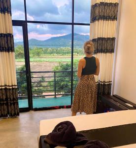 a woman standing in a room looking out of a window at Ridge Boundary View in Dambulla