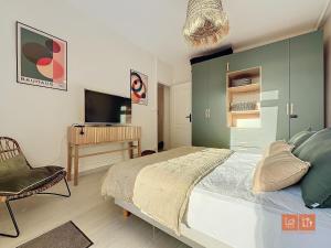 een slaapkamer met een bed, een stoel en een televisie bij Le Mourillon - Centre Ville in Wimereux