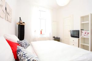 a white bedroom with a bed and a tv at Warnemünde Studio Linser 14481 in Warnemünde