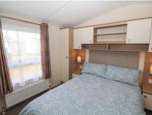una camera da letto con un letto blu e una finestra di Rhodes Retreat, Lake District a Brigham