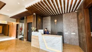 a woman sitting at a reception desk in a lobby at Orbit Regency in Gangtok