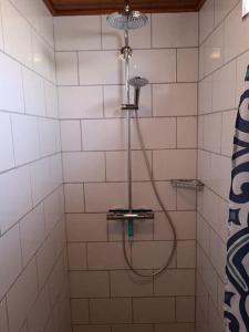 a shower with a hose in a white tiled bathroom at De Stormmeeuw in Egmond aan Zee +18 photos