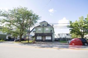 a green house with a red car parked in front of it at 10 Mins to Airport Apt with King Beds in Buffalo