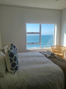 a bedroom with a bed with a view of the ocean at Point Village Accommodation - Ocean Two 43 in Mossel Bay