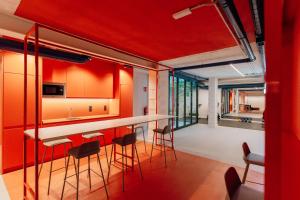 una cocina con paredes rojas y un bar con taburetes en Reliebe 44, en Las Palmas de Gran Canaria