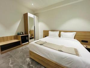 a bedroom with a large white bed and a mirror at Akoya Business Hotel Hyderabad Airpot in Shamshabad +38 photos