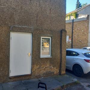 a white door on the side of a building with a car at Wara in Kingston upon Thames