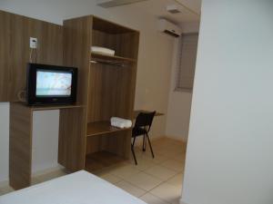 a room with a tv and a desk with a chair at Rota Hotéis in Quirinópolis